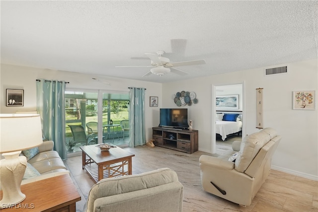 living room with a textured ceiling, ceiling fan, and baseboards