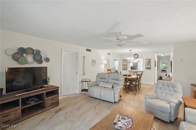 living room featuring ceiling fan, light marble finish flooring, and a textured ceiling