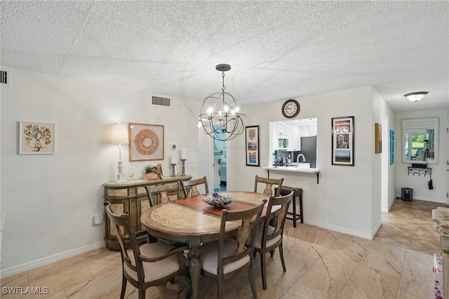 dining area featuring a chandelier, a textured ceiling, and baseboards