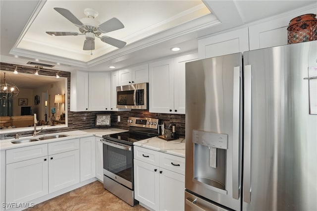 kitchen featuring appliances with stainless steel finishes, a raised ceiling, a sink, white cabinetry, and tasteful backsplash