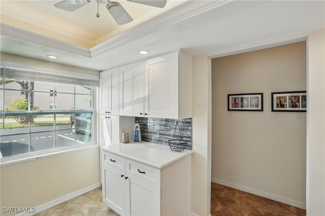 kitchen with ornamental molding, backsplash, white cabinetry, ceiling fan, and light countertops
