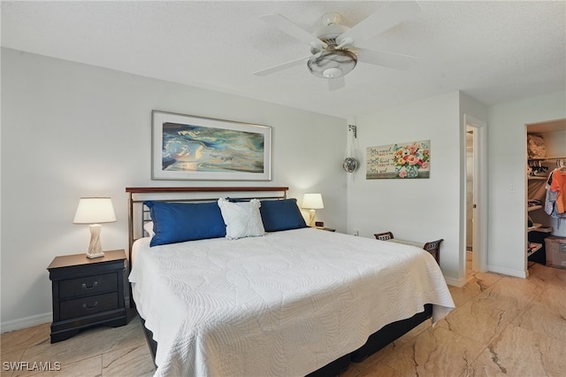 bedroom featuring a walk in closet, baseboards, a closet, and a ceiling fan
