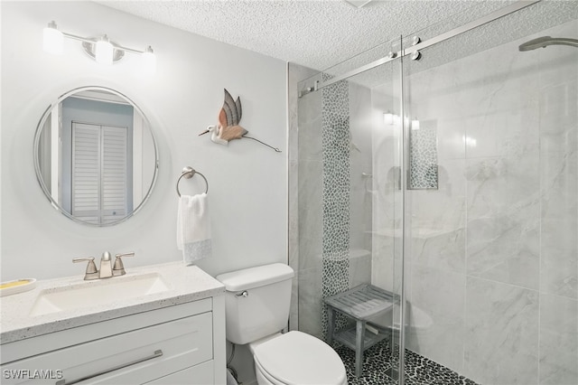 bathroom featuring a textured ceiling, toilet, vanity, and a shower stall