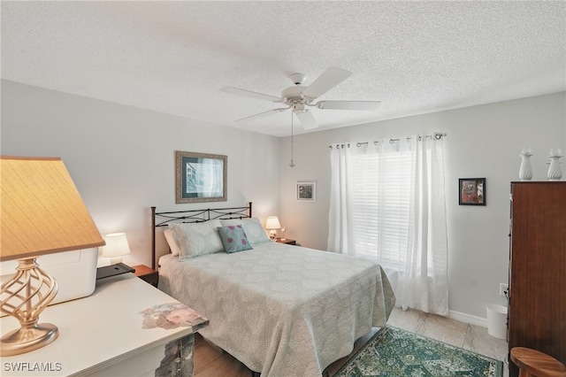 bedroom with a textured ceiling, a ceiling fan, and baseboards