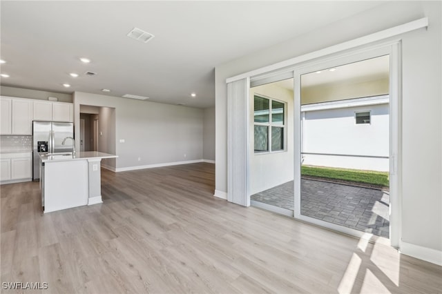 16678 Expedition Ct, Punta Gorda, FL 33982 - kitchen with recessed lighting, white cabinetry, light wood finished floors, a center island with sink, and tasteful backsplash