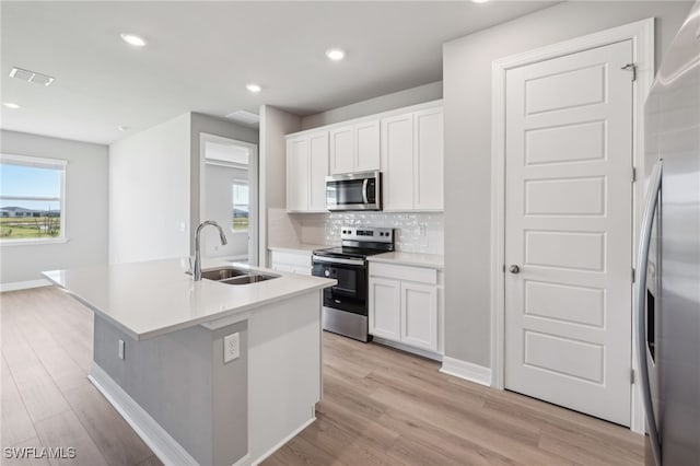 16678 Expedition Ct, Punta Gorda, FL 33982 - kitchen with stainless steel appliances, a sink, decorative backsplash, white cabinets, and light wood-style flooring