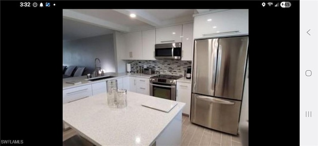 2111 Barkeley Ln Unit 13, Fort Myers, FL 33907 - kitchen featuring stainless steel appliances, white cabinetry, beam ceiling, decorative backsplash, and modern cabinets