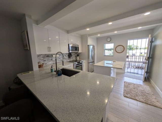 2111 Barkeley Ln Unit 13, Fort Myers, FL 33907 - kitchen with stainless steel appliances, a sink, beam ceiling, tasteful backsplash, and a peninsula