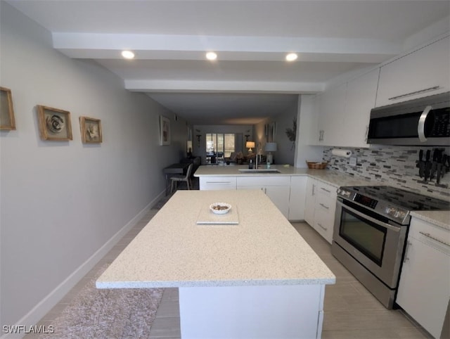2111 Barkeley Ln Unit 13, Fort Myers, FL 33907 - kitchen with stainless steel appliances, a sink, beam ceiling, white cabinetry, and a peninsula