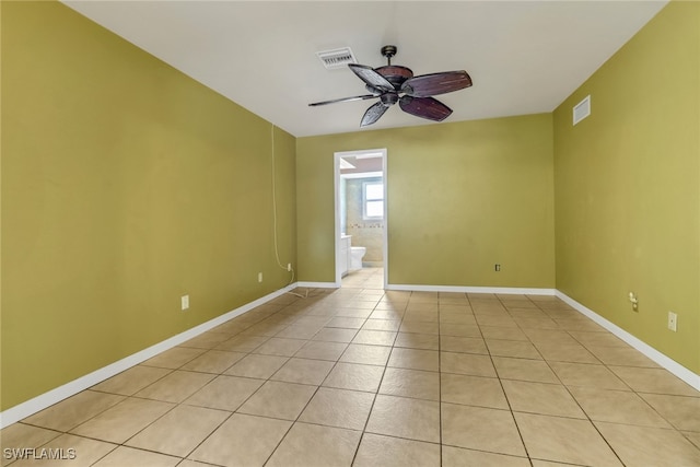 empty room with light tile patterned flooring, a ceiling fan, and baseboards