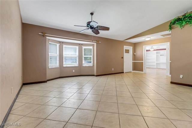 spare room with ceiling fan, vaulted ceiling, baseboards, and light tile patterned floors