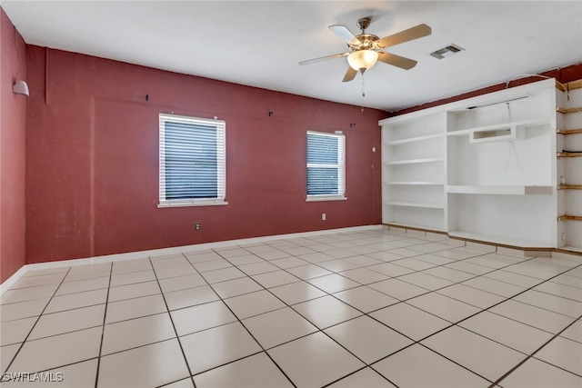 empty room with a ceiling fan, light tile patterned floors, and baseboards
