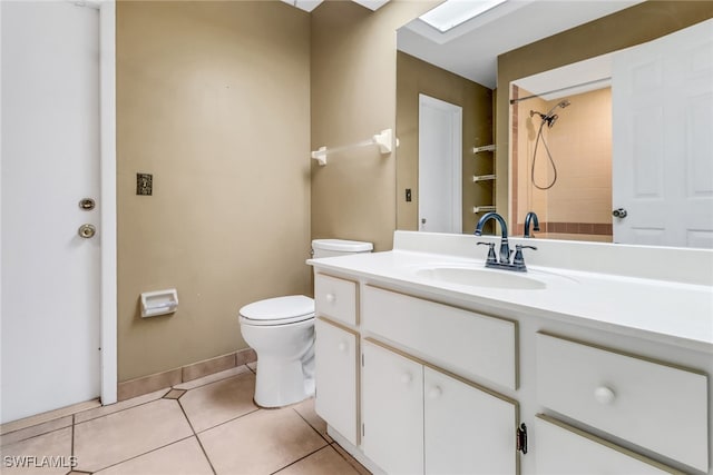 bathroom featuring toilet, tile patterned flooring, vanity, a tile shower, and baseboards