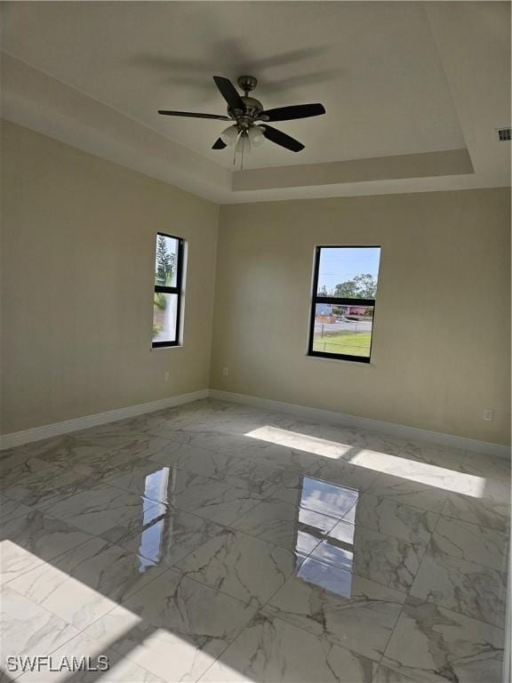 3418 12th St W, Lehigh Acres, FL 33971 - unfurnished room featuring a raised ceiling, baseboards, a ceiling fan, and marble finish flooring
