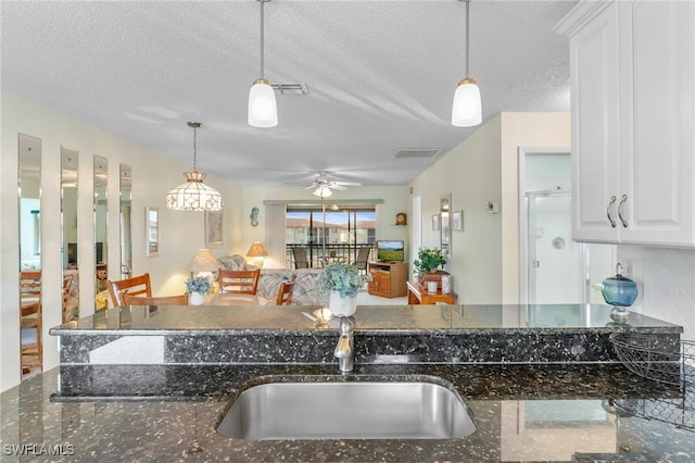 25100 Sandhill Blvd Unit R202, Punta Gorda, FL 33983 - kitchen with a sink, a textured ceiling, decorative light fixtures, white cabinets, and dark stone counters