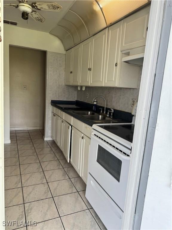 5 Desert Candle Cir, Lehigh Acres, FL 33936 - kitchen featuring white range with electric cooktop, a sink, dark countertops, ceiling fan, and white cabinetry