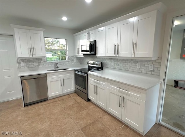 803 Monroe Dr, Lehigh Acres, FL 33936 - kitchen with stainless steel appliances, a sink, decorative backsplash, light countertops, and white cabinetry