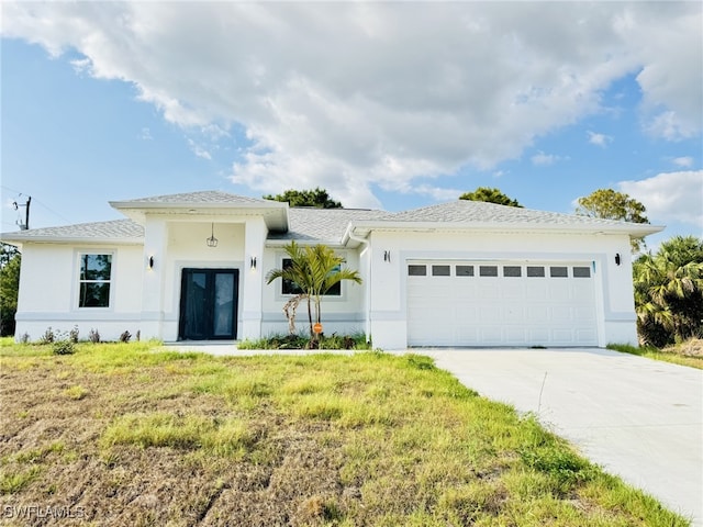 16 W 7th St, Lehigh Acres, FL 33972 - view of front of house featuring a garage, concrete driveway, stucco siding, a front yard, and french doors