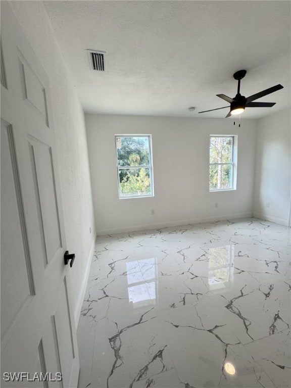 16 W 7th St, Lehigh Acres, FL 33972 - unfurnished room featuring baseboards, marble finish floors, and a ceiling fan