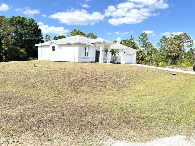 16 W 7th St, Lehigh Acres, FL 33972 - view of front of property with an attached garage, a front yard, driveway, and stucco siding