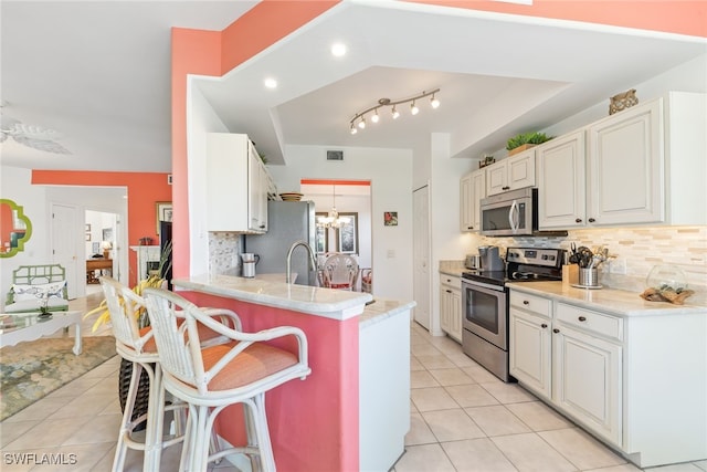 14521 Grande Cay Cir Unit 2902, Fort Myers, FL 33908 - kitchen with stainless steel appliances, light tile patterned floors, backsplash, a kitchen bar, and a chandelier
