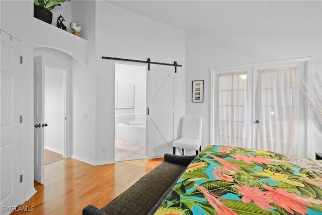 12839 Oakpointe Cir, Fort Myers, FL 33912 - bedroom featuring a barn door, light wood-style flooring, a towering ceiling, arched walkways, and ensuite bath