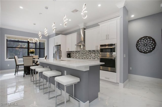 610 25th Ave NW, Naples, FL 34120 - kitchen featuring wall chimney range hood, tasteful backsplash, a large island, crown molding, and light marble finish flooring
