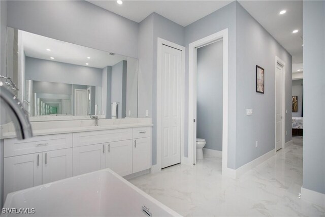 610 25th Ave NW, Naples, FL 34120 - ensuite bathroom with marble tiled floors, toilet, recessed lighting, baseboards, and vanity