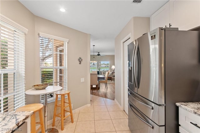 13020 Amberley Ct Unit 301, Bonita Springs, FL 34135 - kitchen featuring stainless steel fridge with ice dispenser, white cabinetry, light tile patterned flooring, light stone countertops, and ceiling fan