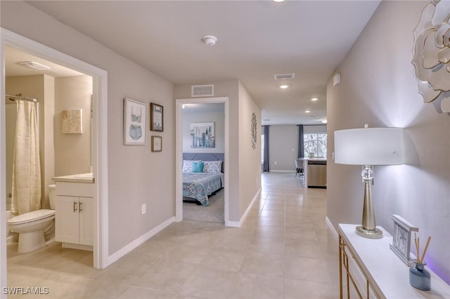 hall featuring light tile patterned flooring, baseboards, and recessed lighting