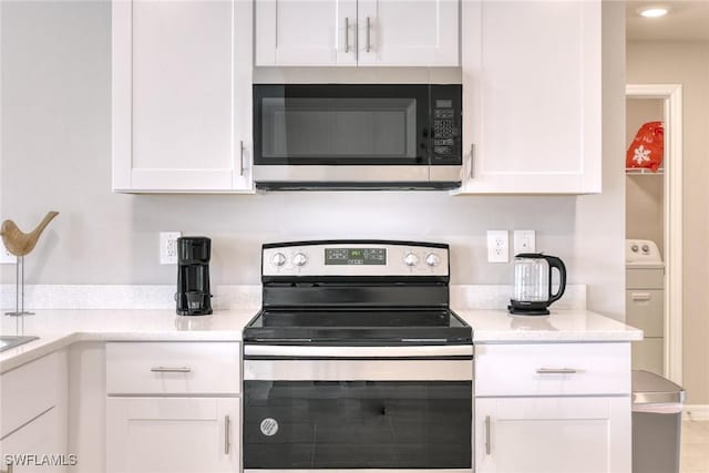 kitchen with stainless steel appliances, white cabinets, and washer / dryer