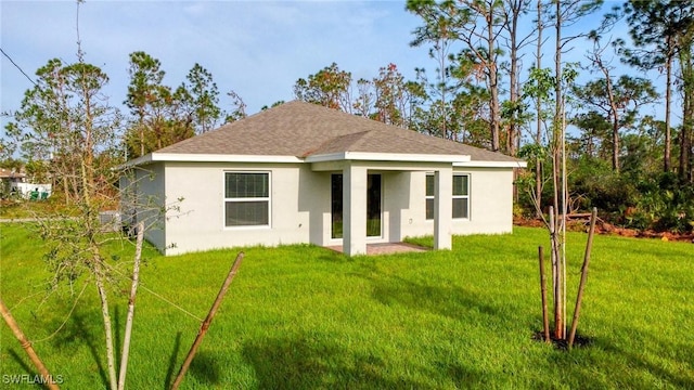 back of house featuring stucco siding, a lawn, and a shingled roof