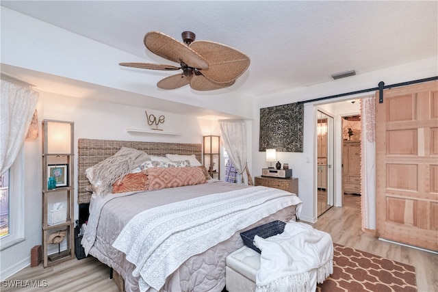 28427 Sabal Palm Dr, Punta Gorda, FL 33982 - bedroom with light wood finished floors, a barn door, a ceiling fan, and baseboards