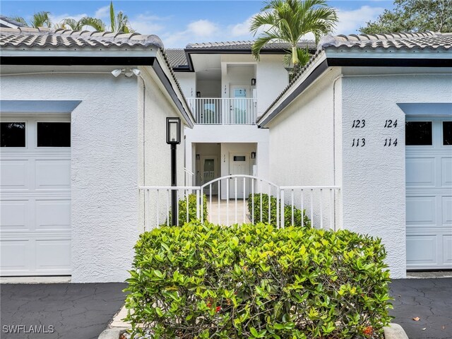 2110 Cay Lagoon Dr Unit 113, Naples, FL 34109 - view of exterior entry featuring stucco siding, a tile roof, and a balcony