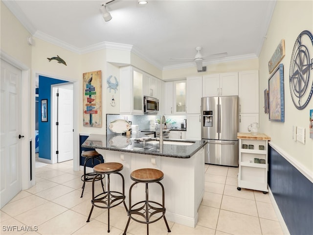 2110 Cay Lagoon Dr Unit 113, Naples, FL 34109 - kitchen with stainless steel appliances, light tile patterned flooring, dark stone counters, white cabinetry, and glass insert cabinets