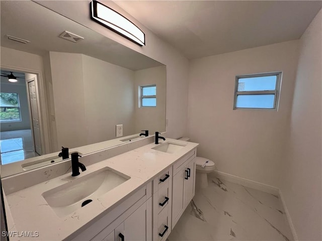 bathroom featuring baseboards, healthy amount of natural light, marble look tiles, and toilet