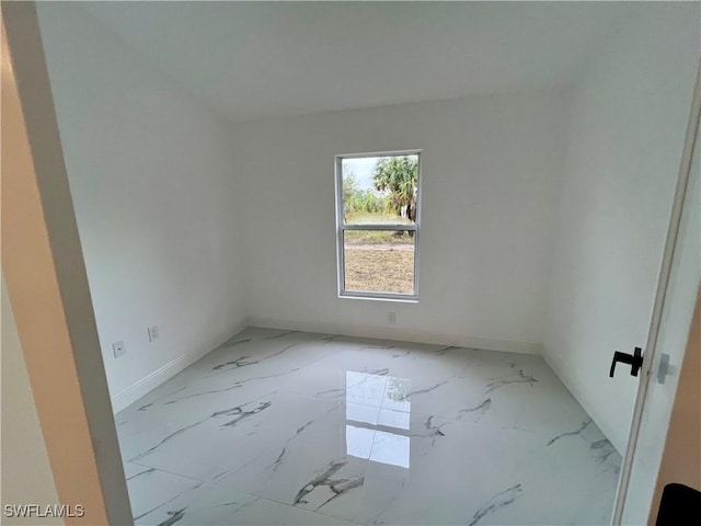 spare room featuring marble finish flooring and baseboards