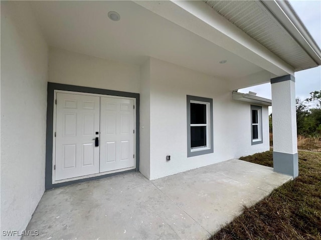 doorway to property featuring stucco siding and a patio area