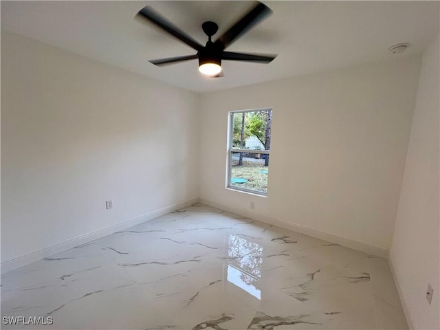 spare room featuring baseboards, light marble finish flooring, and ceiling fan
