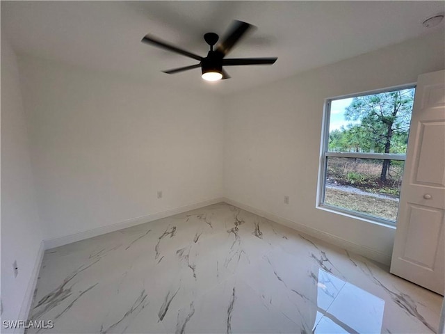 spare room featuring baseboards, ceiling fan, and light marble finish flooring