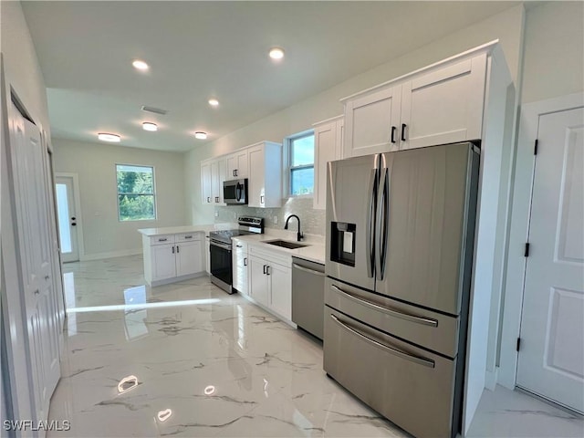 kitchen with stainless steel appliances, a sink, light marble finish flooring, white cabinets, and recessed lighting