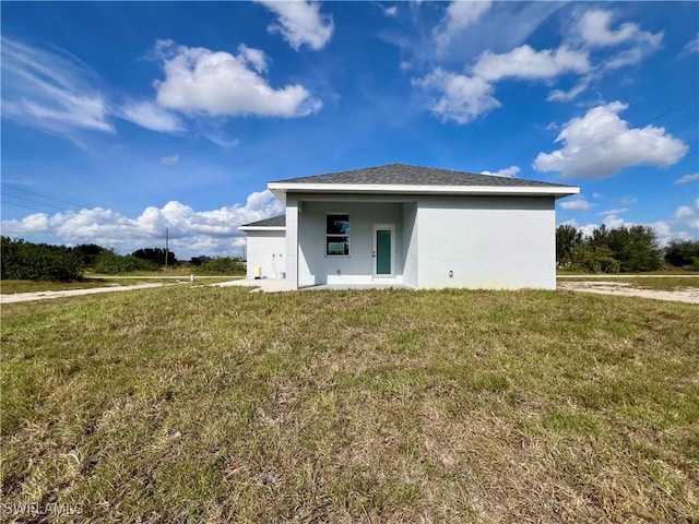 rear view of house with a yard and stucco siding