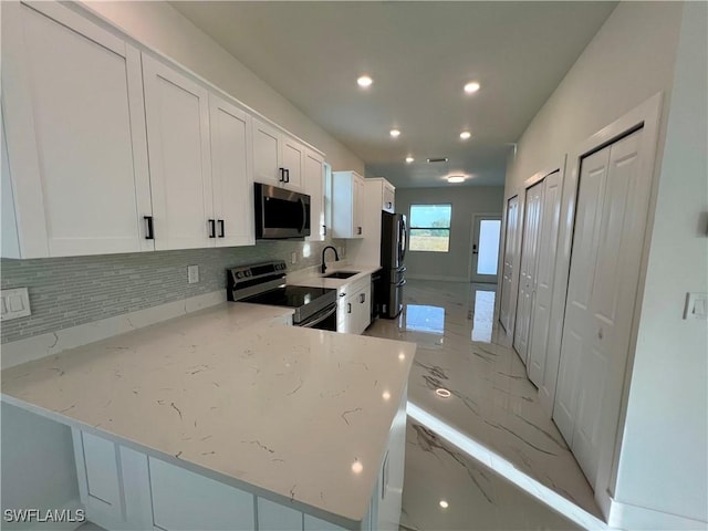 kitchen featuring appliances with stainless steel finishes, a sink, decorative backsplash, white cabinets, and recessed lighting