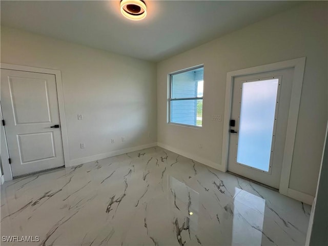 doorway with baseboards and light marble finish flooring
