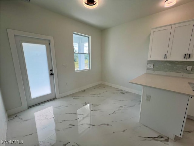 unfurnished dining area with baseboards and light marble finish flooring