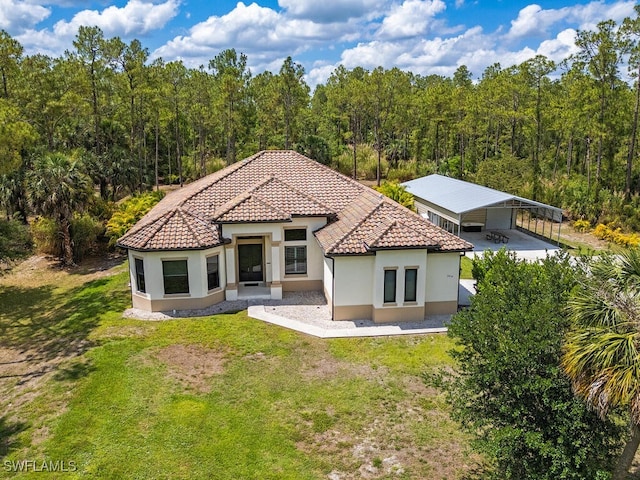 3818 2nd Ave NE, Naples, FL 34120 - back of house with stucco siding, a tiled roof, a lawn, a view of trees, and a carport