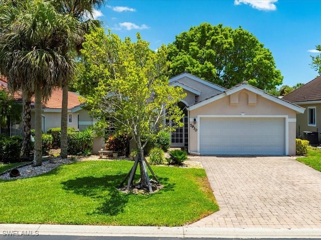 7930 Wexford Dr, Naples, FL 34104 - view of front of house with central AC unit, stucco siding, an attached garage, a front yard, and driveway