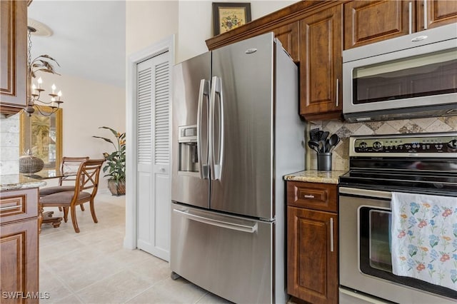 3471 Ballybridge Cir Unit 202, Bonita Springs, FL 34134 - kitchen featuring stainless steel appliances, tasteful backsplash, light stone countertops, and light tile patterned floors