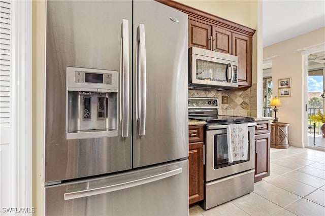 3471 Ballybridge Cir Unit 202, Bonita Springs, FL 34134 - kitchen featuring appliances with stainless steel finishes, decorative backsplash, light tile patterned floors, light stone countertops, and baseboards