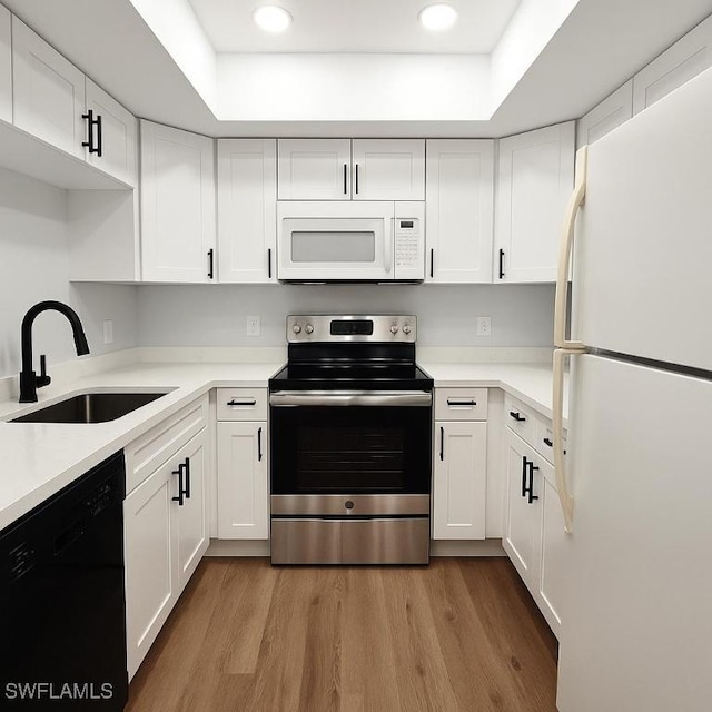 kitchen featuring white appliances, a sink, white cabinetry, wood finished floors, and recessed lighting